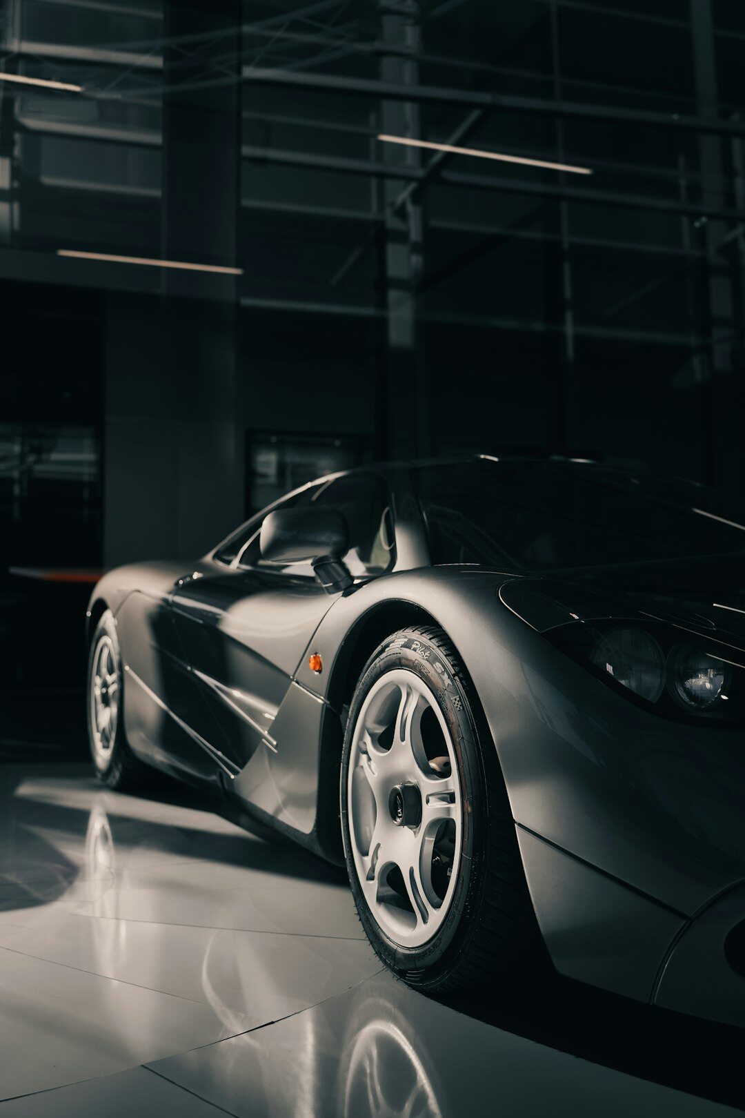 Modern V12 hypercar photographed in a dark studio with dramatic rim lighting